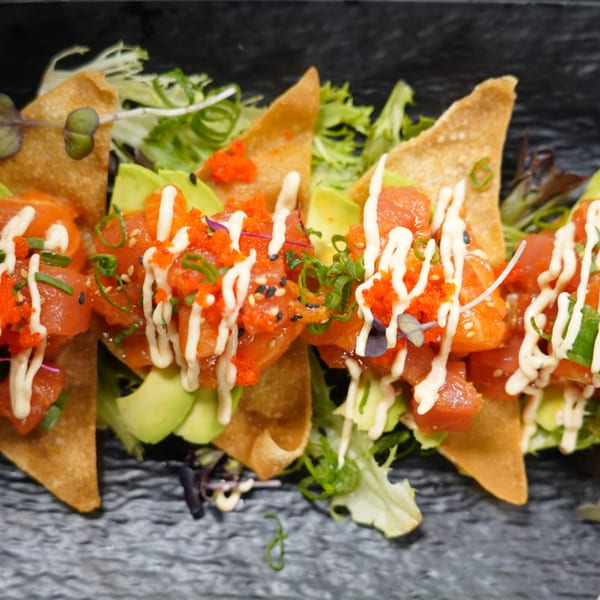 MISO Ramen and Poke Bar's tuna poke nachos with avocado, roe, and creamy sauce on a dark plate.