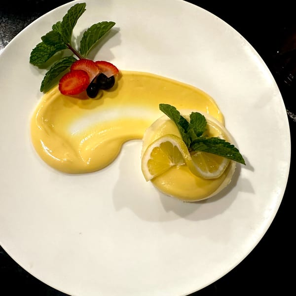 A lemon dessert with mint, strawberries, and blueberries on a white plate.