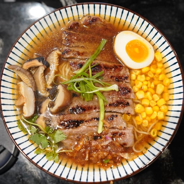 MISO Ramen bowl with sliced beef, mushrooms, corn, a soft-boiled egg, and green onions.